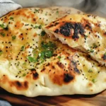 Golden sourdough discard naan brushed with butter, sprinkled with cilantro and black sesame seeds.