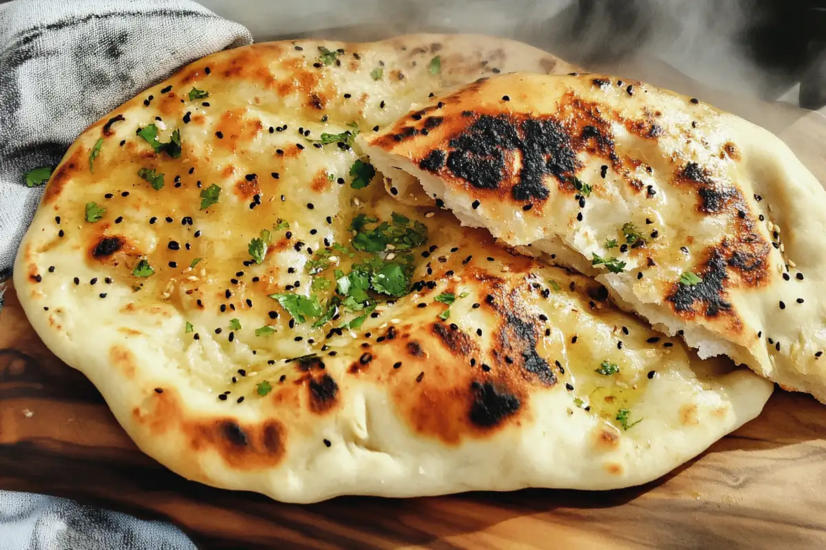 Golden sourdough discard naan brushed with butter, sprinkled with cilantro and black sesame seeds.