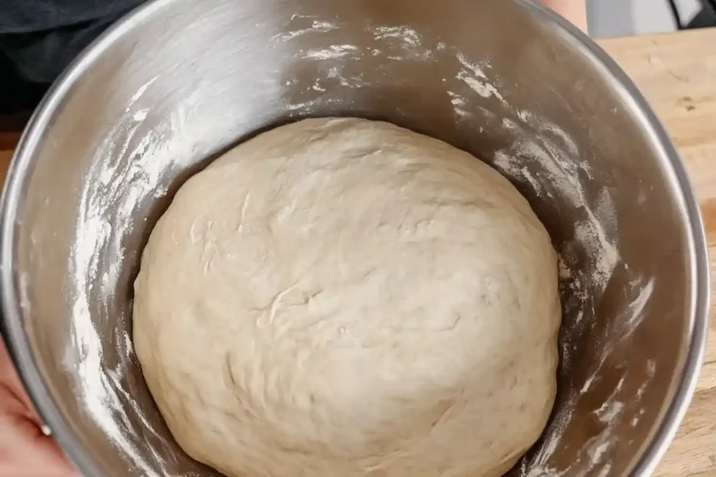 A bowl of sourdough garlic bread dough after initial mixing, smooth and slightly elastic, ready for its first rise.