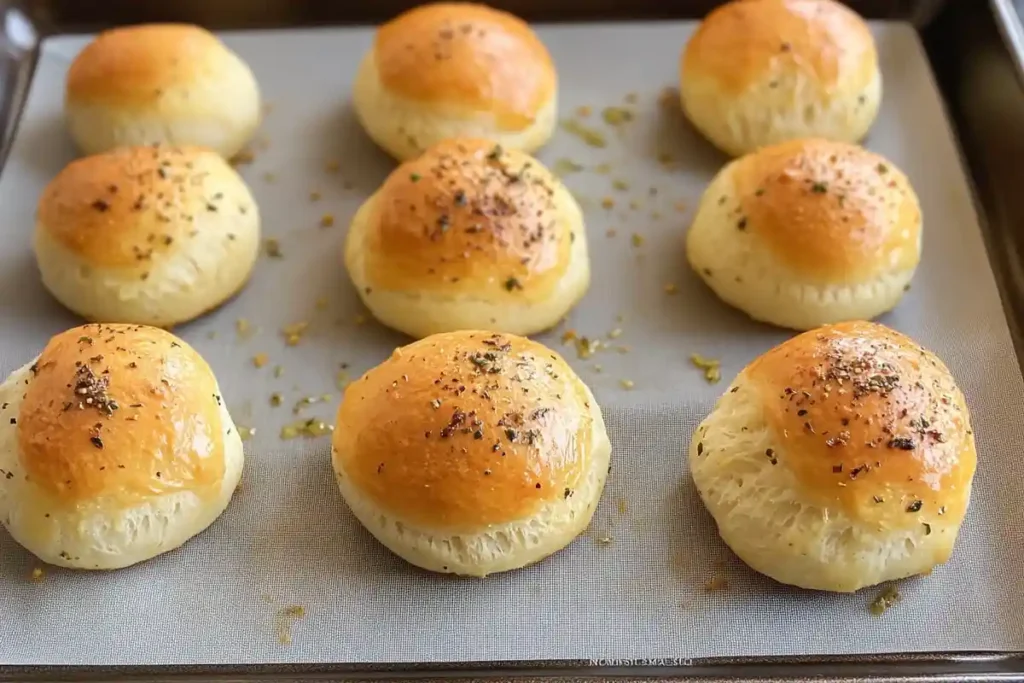 A baking tray filled with golden, fluffy garlic butter cheese bombs topped with garlic and parsley.