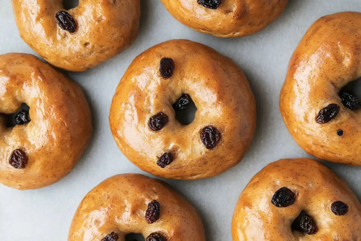 Top-down view of glossy sourdough cinnamon raisin bagels with raisins on a parchment-lined surface