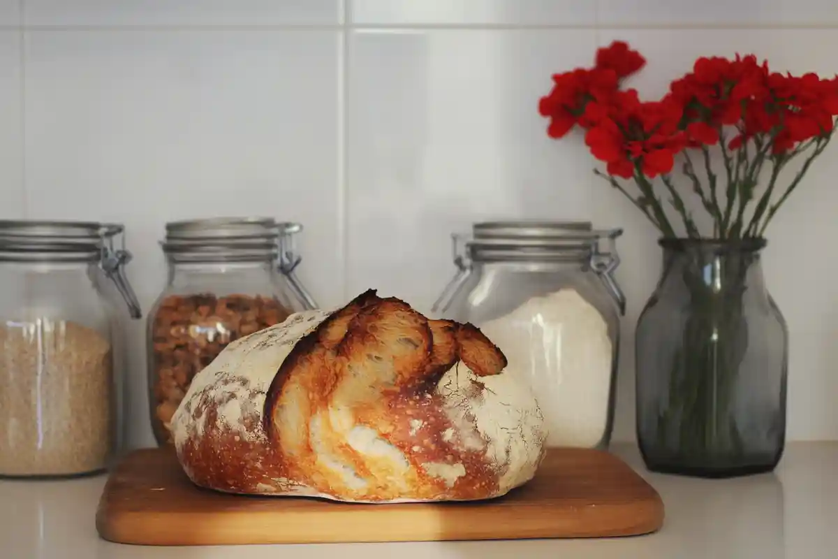 A close-up of a sourdough bread slice with large, irregular air pockets and a flattened shape, showing signs of overproofing.